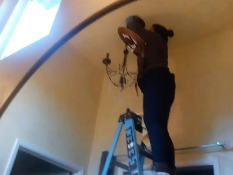 Electrician installing a chandelier in a Poway residence